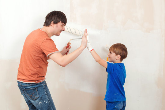 Father and son painting a wall. Young family painting house wall.