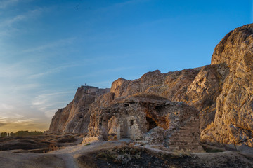 Evening view onto ruins of building (mosque or church) in Old City of Van, Van, Turkey. Van Rock with its famous fortress is on background. Rock & ruins are painted with golden light of sunset