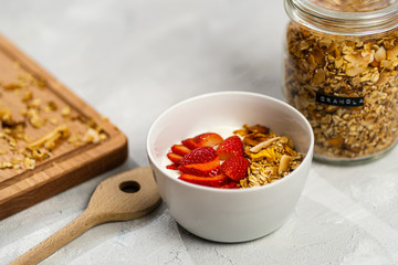 Fresh homemade cocos-mango granola with yoghurt and fresh strawberries. 