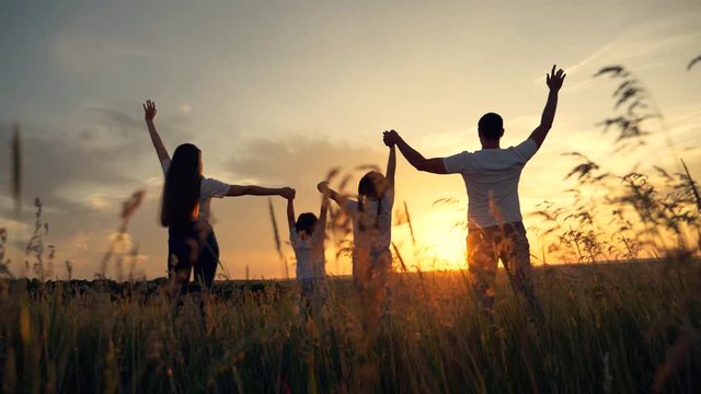 Beautiful people raise their hands up to the sun at sunset. Leisure healthy lifestyle, travel. Happy kids with parents. Happy family in the park in the open air.