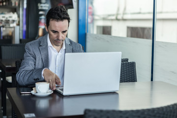 Fototapeta na wymiar Busy man working with laptop in cafe