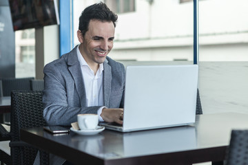 Fototapeta na wymiar Happy businessman working with laptop in modern cafe