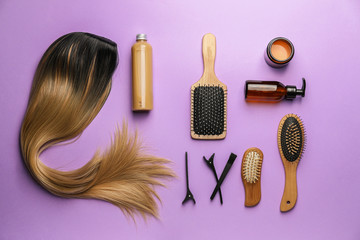 Unusual wig with hairdresser supplies on color background