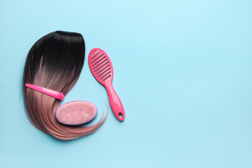 Unusual wig with hairdresser supplies on color background