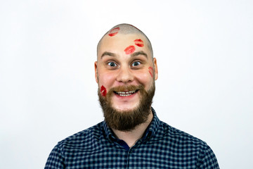 Happy man with traces of kisses on his head. Guy face in lipstick.