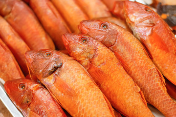 Grilled red mullet, smoked fish arranged in several rows on a tray
