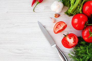 Fresh vegetables and knife on the white wooden table. Healthy food concept. Salad cooking process...