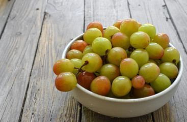 Ripe large grapes. Grapes in a plate isolated on a wooden background. Free space for text.
