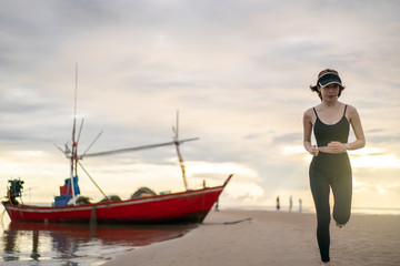 Woman in sportswear jogging on quayside beach in the morning.