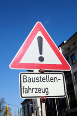 Verkehrsschild Gefahrstelle, Baustellenfahrzeuge, Blauer Himmel, Deutschland