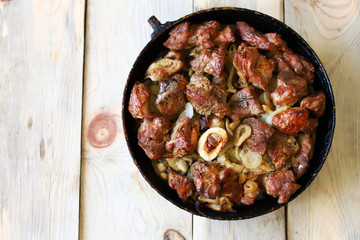 Selective focus. Fried meat pieces in a frying pan. Appetizing grilled meat with onions. Cooked pork.