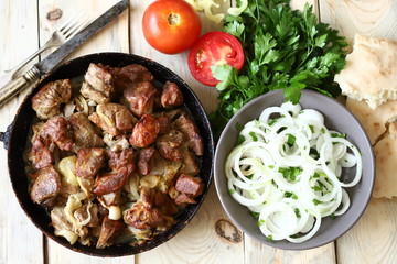 Selective focus. Fried meat pieces in a frying pan. Appetizing grilled meat with onions. Cooked pork.