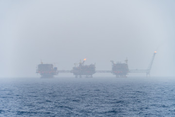 Misty morning at oil filed with a oil production platform complex in the background