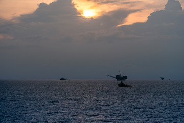 Supply boat steaming at an oil field during sunrise