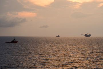 Supply boat and diving vessel steaming at an oil field during sunrise