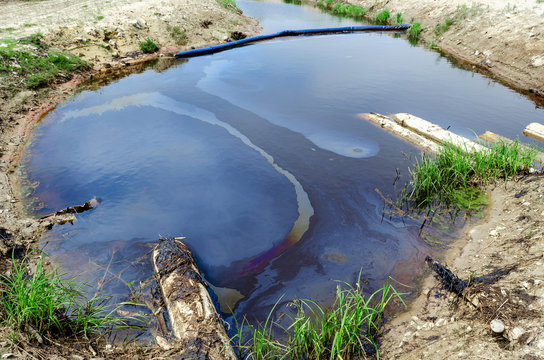 Oil spill in the reservoir. Rainbow spots on the surface of the water. Environmental problem.
