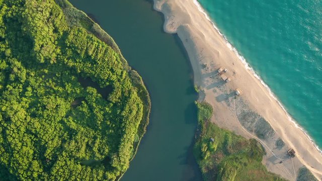 Drone flight over a river that passes by a forest, a wild sandy beach and flows into the sea. The mouth of the river forms a beautiful strip of sand at its confluence, Veleka River, Bulgaria.