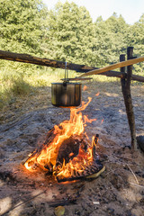 Camping, a pot of water boils over the fire.