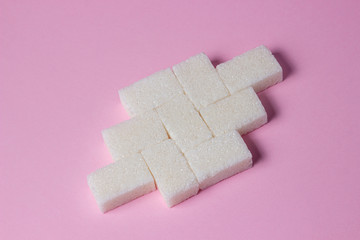 Sugar cubes on a pink background. Sugar cubes are folded into a shape.