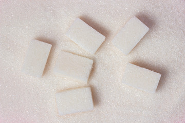 Sugar cubes lie on granulated sugar. Photo from above.