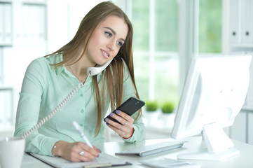 Obraz na płótnie Canvas Portrait of businesswoman talking on phone in office