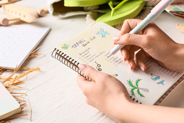 Woman making check-list of things to pack for travel