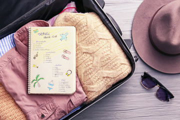 Notebook with check-list for travel and packed things in suitcase