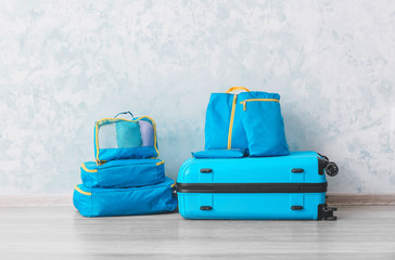 Set of travel organizers with belongings and suitcase on floor at home