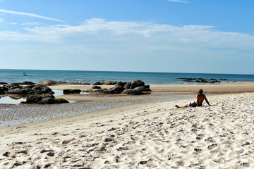 Fototapeta na wymiar Summer beach vacation concept, man relaxing on beach, ocean sunny view