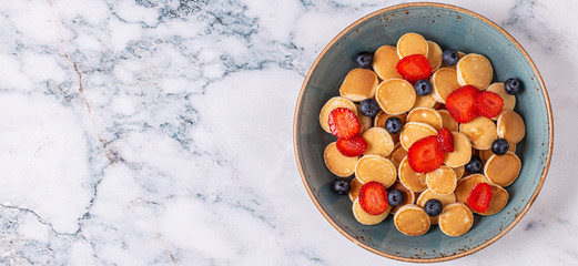 Trendy breakfast with mini pancakes, blueberries and strawberries