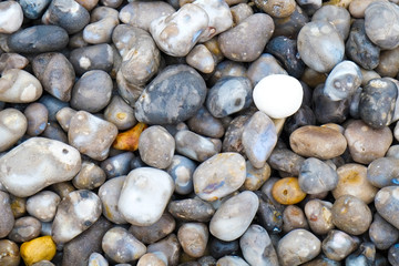 Close up of the pebbles on a beach in Normandy France, creating an Abstract smooth round pebbles sea texture background 
