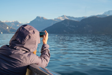 Tourists are taking photos by smartphone include river and mountains against sky in Luzern Switzerland