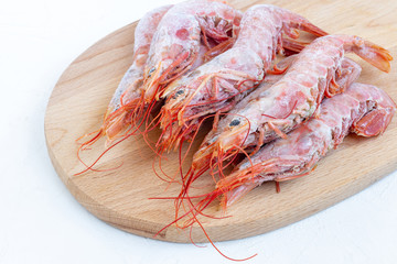 Fresh frozen langoustines (big shrimps) on wooden board