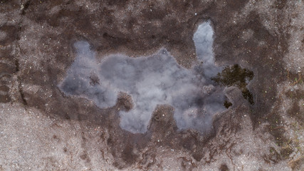 Huge puddle and dirt aerial top-down view. Cloud reflection in water.