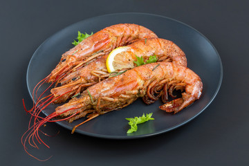 Tiger shrimp (Langoustine) fried with lemon, garlic and rosemary on a black background. Seafood