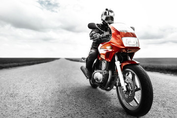 A man rides a red motorcycle on the road. Black and white photo