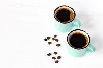 Obraz na płótnie Canvas Two azure cups of fresh coffee with grains on white wooden background. Copy space