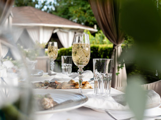 Glasses of champagne on a set table in an open-air restaurant.