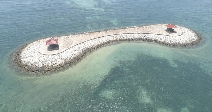 Slow drone orbit of man-made land strip on a coral reef