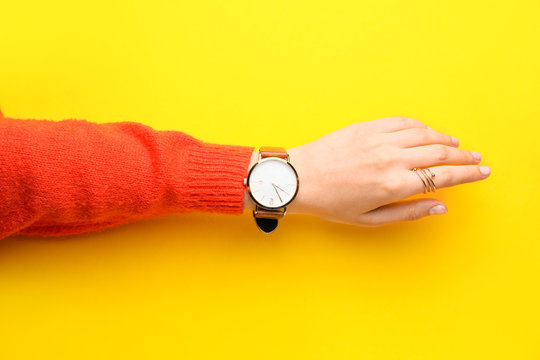 Female hand with stylish wrist watch on color background