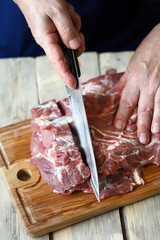 Selective focus. The chef cuts raw meat on the board. Pork neck. Cooking pork.