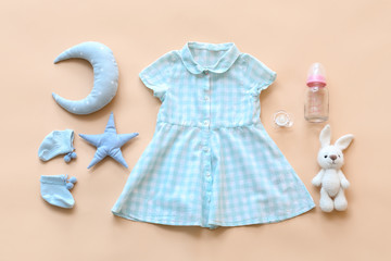 Baby clothes with bottle, pacifier and toys on color background