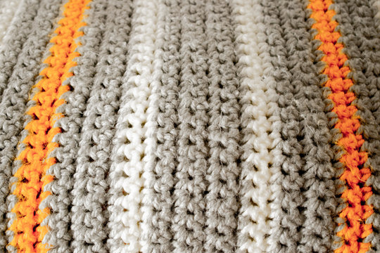 Manta a rayas hecha a mano a ganchillo o crochet en blanco, gris y naranja