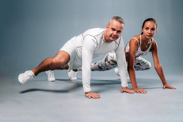 Obraz premium Young sports couple engaged in fitness on a gray background