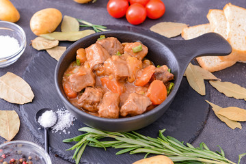 Frying pan with tasty beef stew on dark background