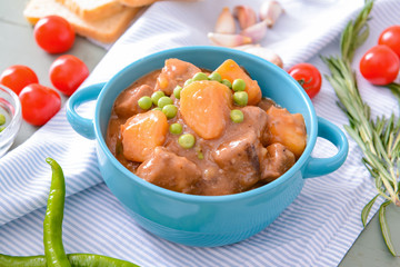 Pot with tasty beef stew on table