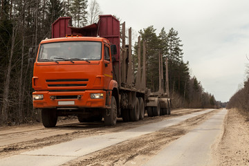 Orange empty Russian timber truck on a dirt road