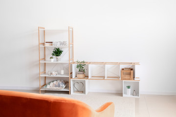 Stylish stand and rack with decor near light wall in room