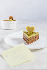 A slice of chocolate mint cake with matcha, a heart of white chocolate and a note 
