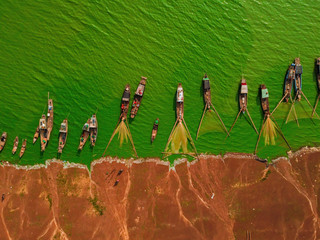 Obraz na płótnie Canvas Aerial view of Ben Nom fishing village, a brilliant, fresh, green image of the green algae season on Tri An lake, with many traditional fishing boats anchored